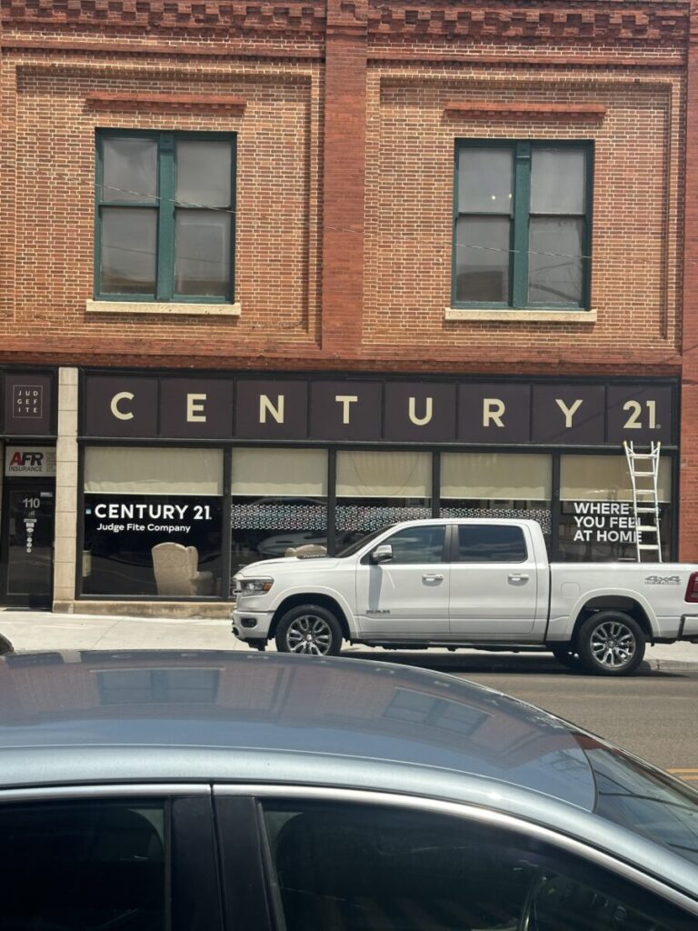 Streetside outdoor sign on building above shop windows